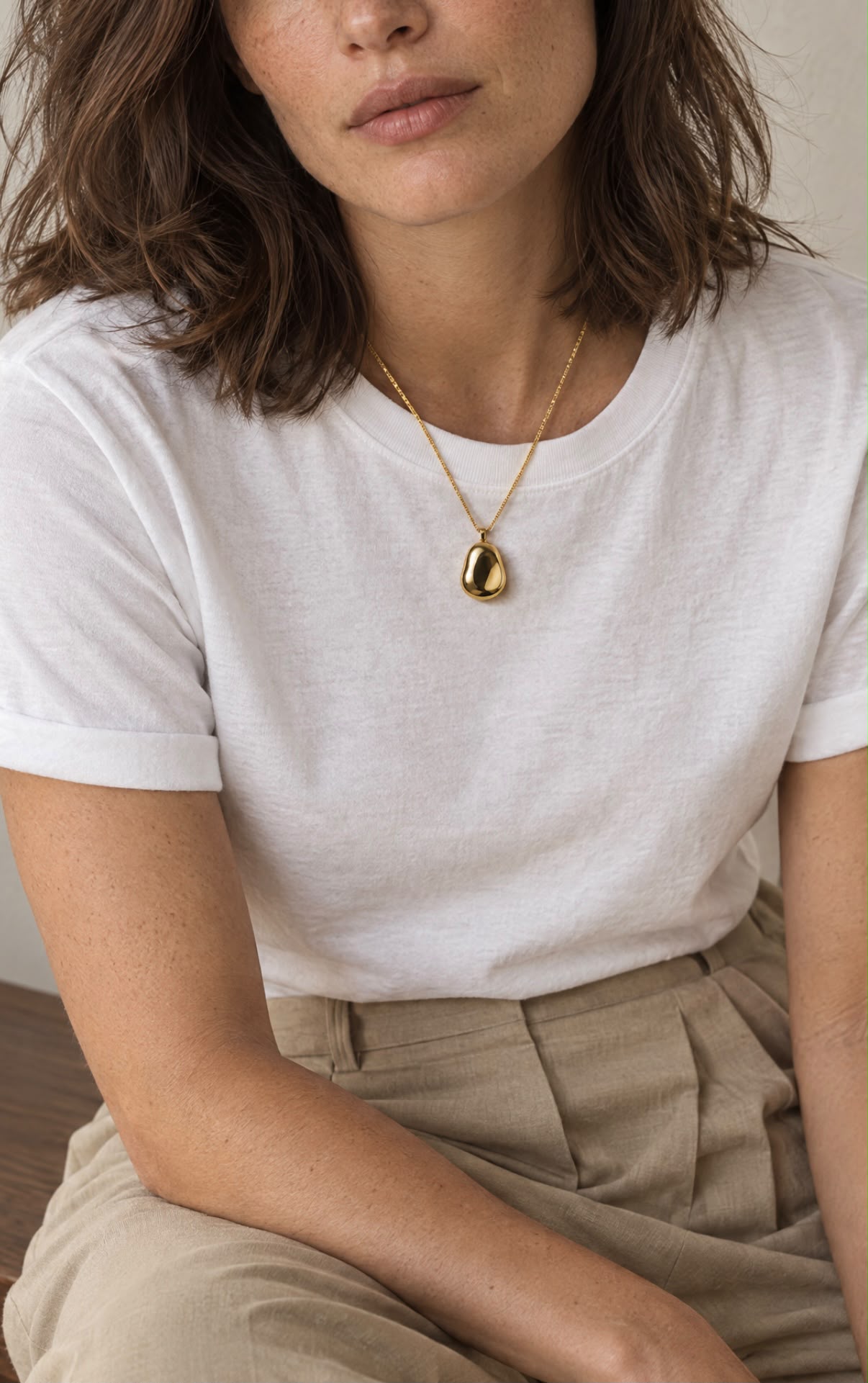 White T-shirt with a small rounded gold pendant