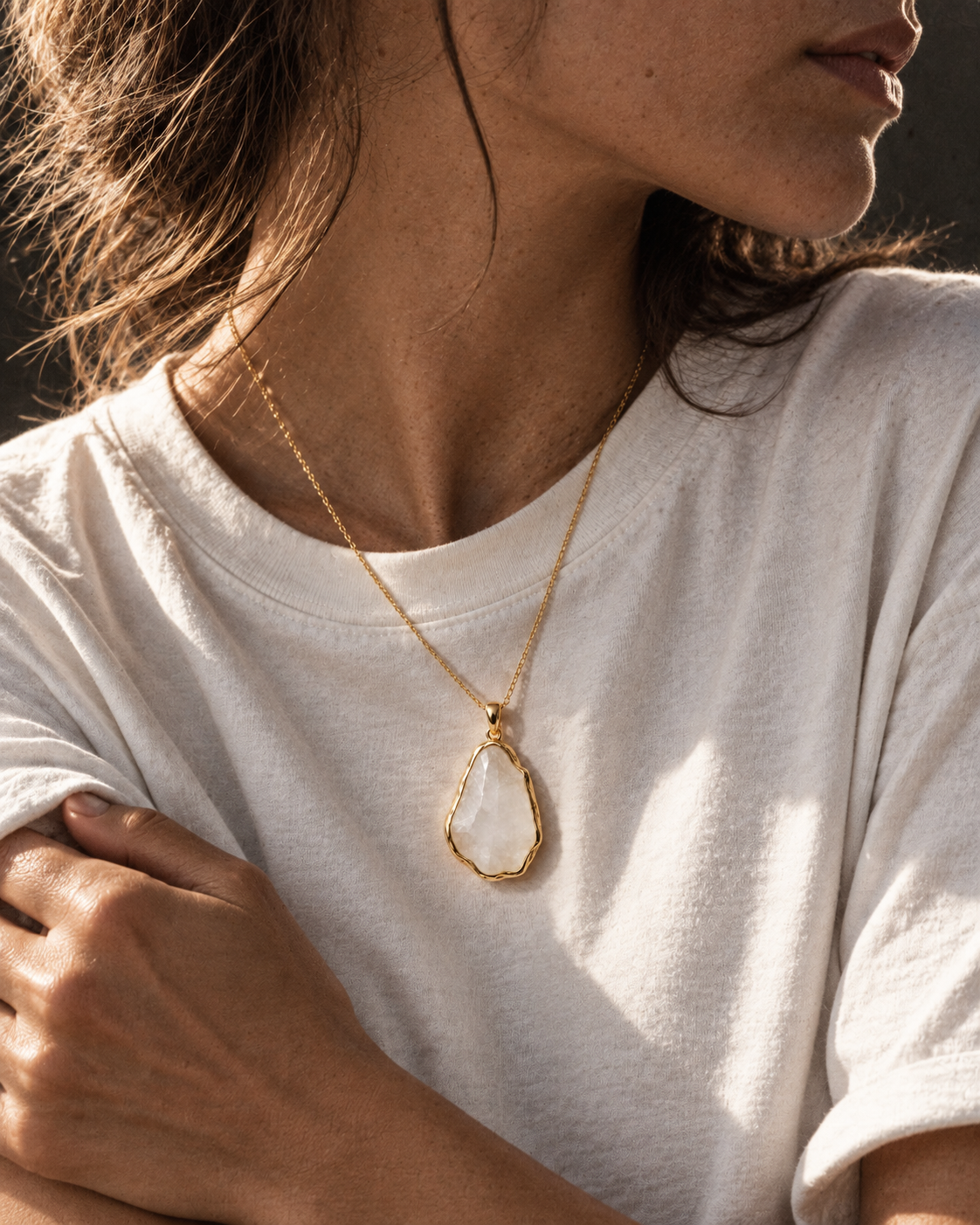 Editorial concept: pale stone pendant on a white T-shirt in a side-angle crop